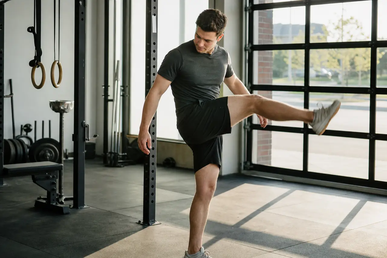 A person doing a dynamic leg swing warm-up in a bright gym before training