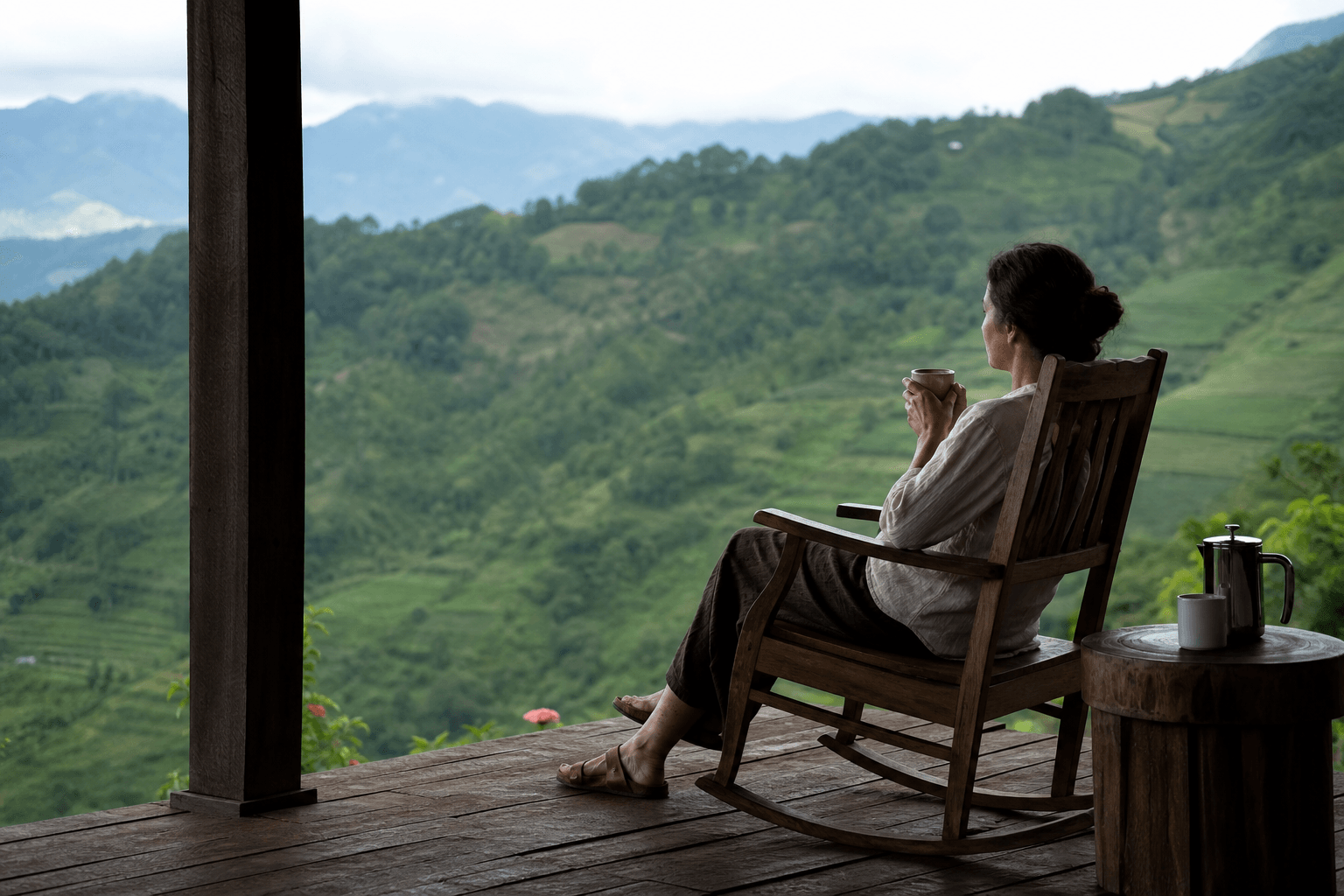 A person resting quietly on a porch looking out at calm green hills, unhurried and at ease