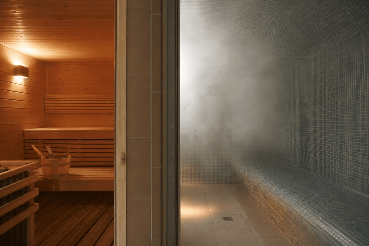 A wooden dry sauna on one side and a tiled steam room filled with mist on the other, warm and inviting