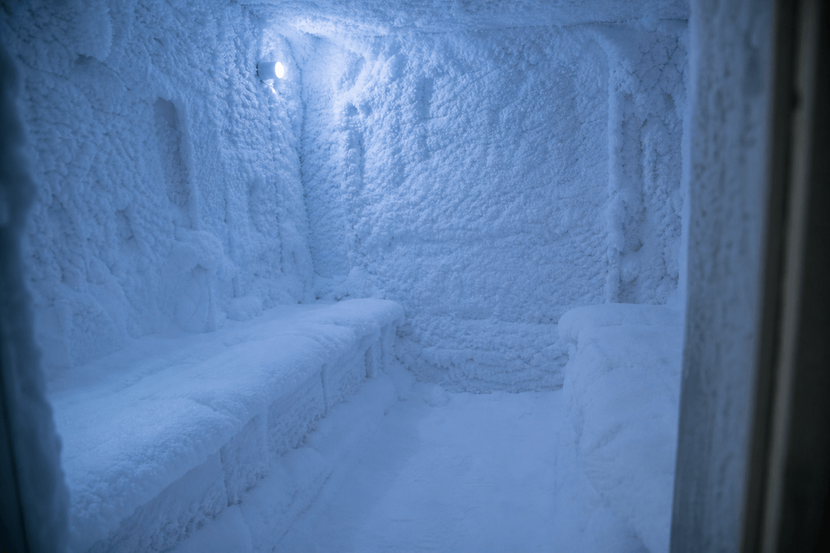 A small refrigerated room with snow-covered benches and walls lit by cool blue light