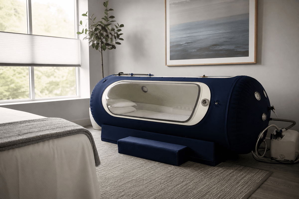 A clean clinic room with a soft-sided hyperbaric chamber, a folded blanket and calm daylight