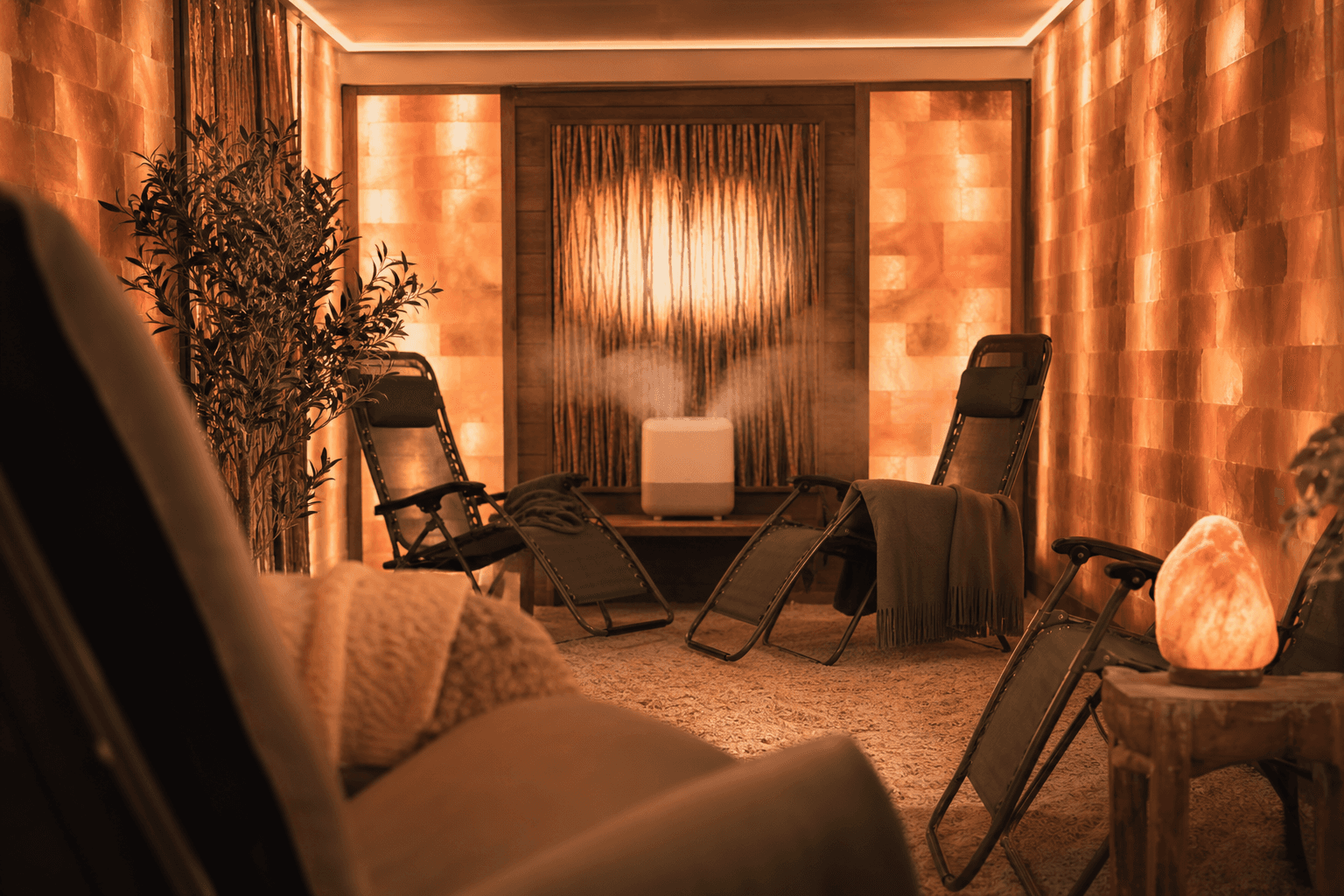 A serene salt therapy room with glowing amber walls made of Himalayan salt bricks, zero-gravity chairs facing a halogenerator, soft warm lighting and misty air
