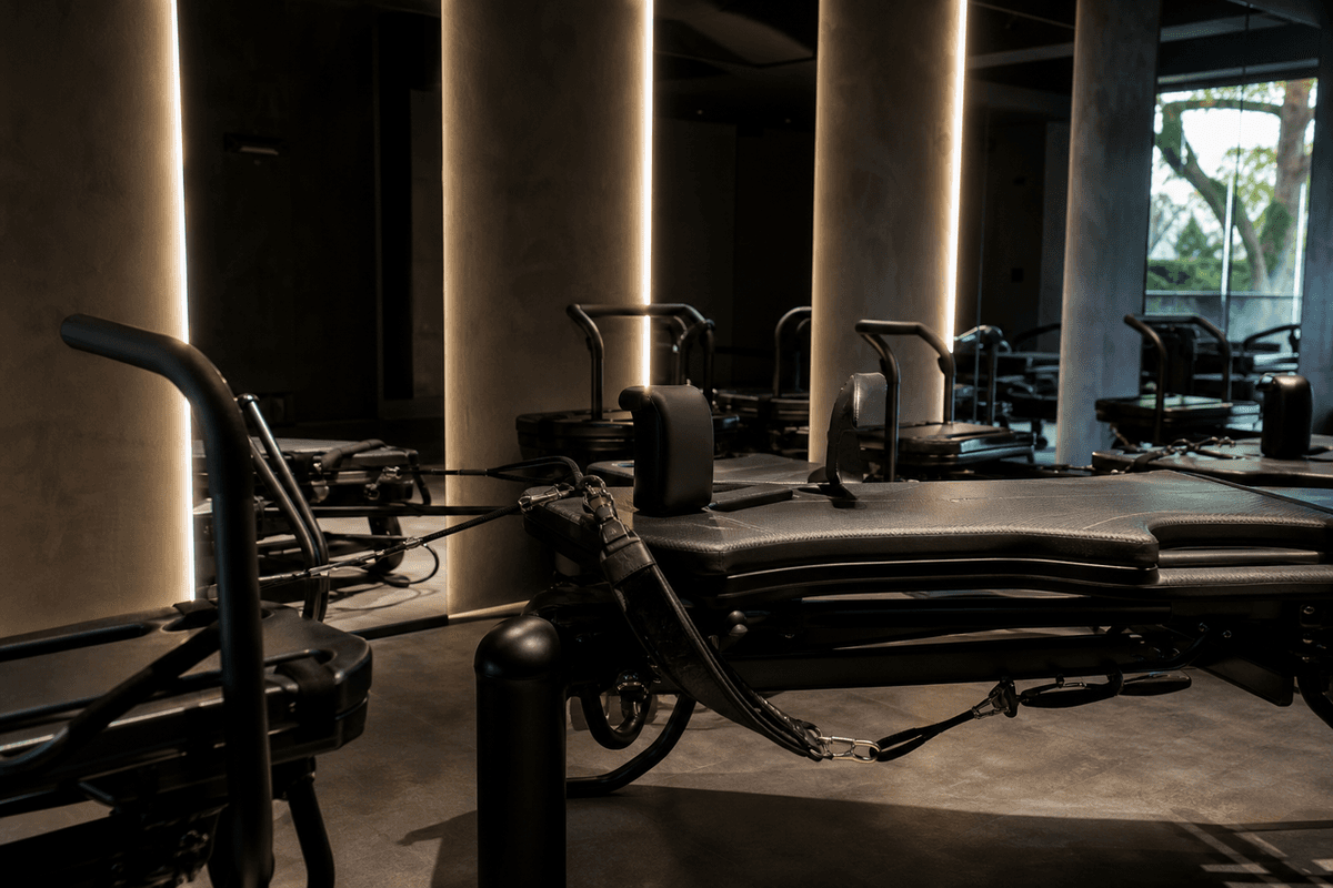 A sleek Megaformer machine in a dark boutique studio with dramatic lighting