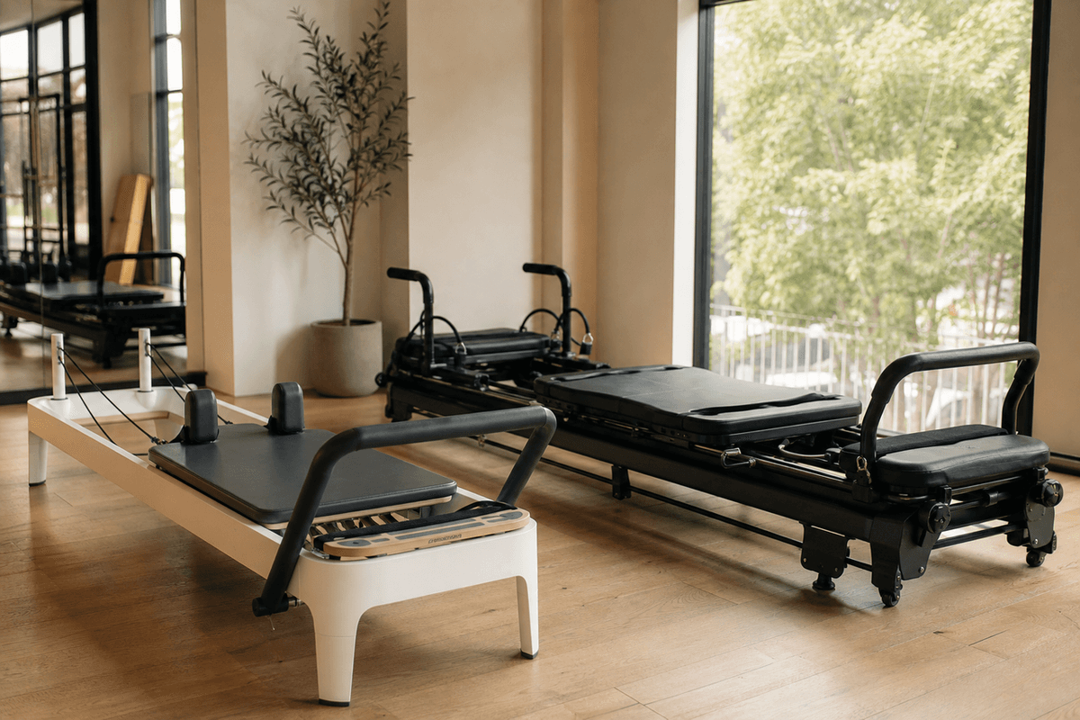 A Pilates reformer and a larger Megaformer side by side in a bright studio