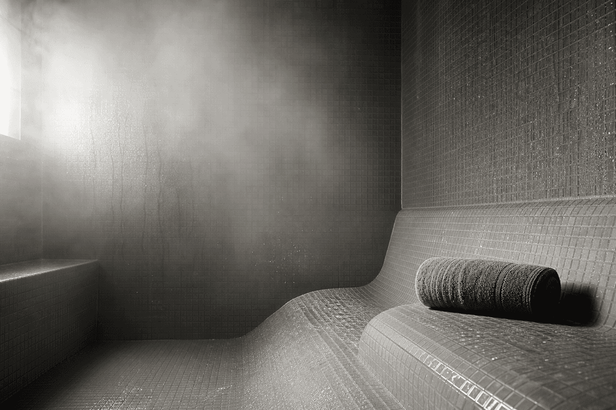 A steam room bench with condensation on tiled walls and soft diffused light